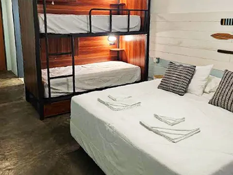 Quarto com beliche e cama de casal com almofadas listradas