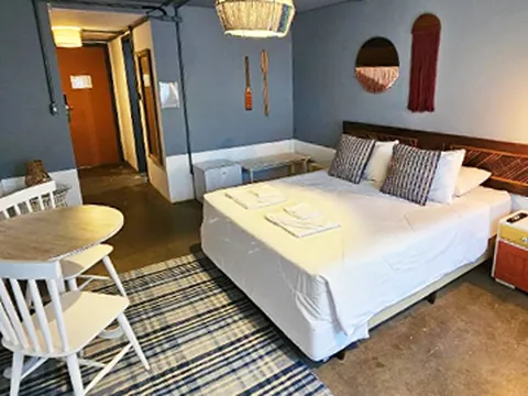 Quarto com cama de casal, cadeiras brancas e tapete listrado