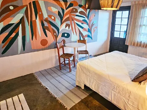 Quarto com mural de folhas, luminária de palha e cama de casal