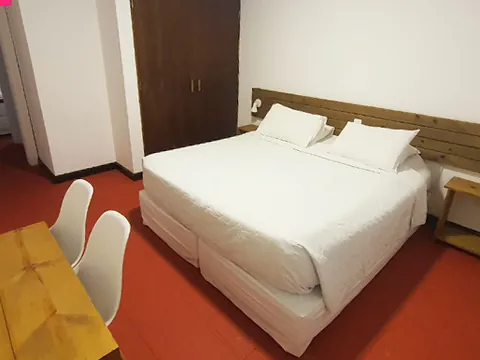 Quarto com cama de casal, guarda-roupa de madeira e piso vermelho