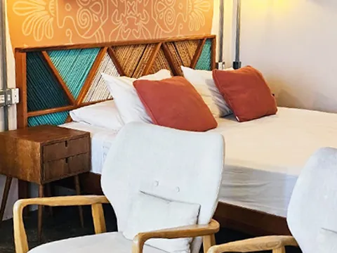 Quarto com cabeceira em mandala, almofadas terracota e poltrona